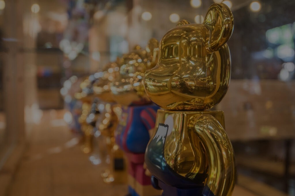 Golden Bearbrick figure gleams in a lineup, reflecting ambient light in a display case—highlighting luxury and collectible artistry.